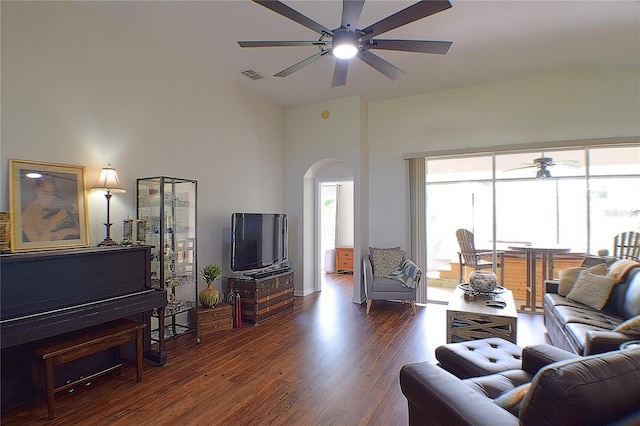 living area with a high ceiling, visible vents, arched walkways, ceiling fan, and dark wood-style flooring
