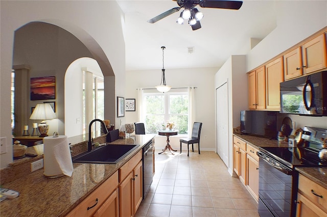 kitchen with a sink, a ceiling fan, dark stone countertops, light tile patterned floors, and black appliances