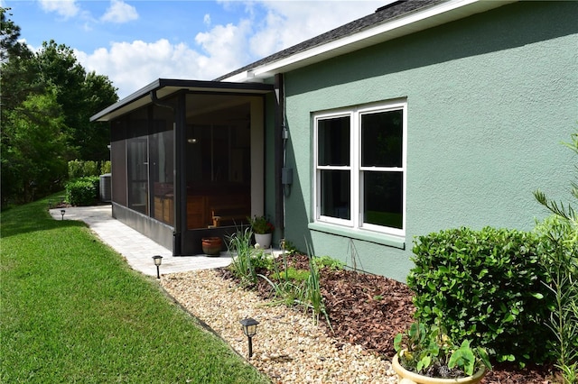 view of home's exterior featuring a lawn, stucco siding, a sunroom, and central AC
