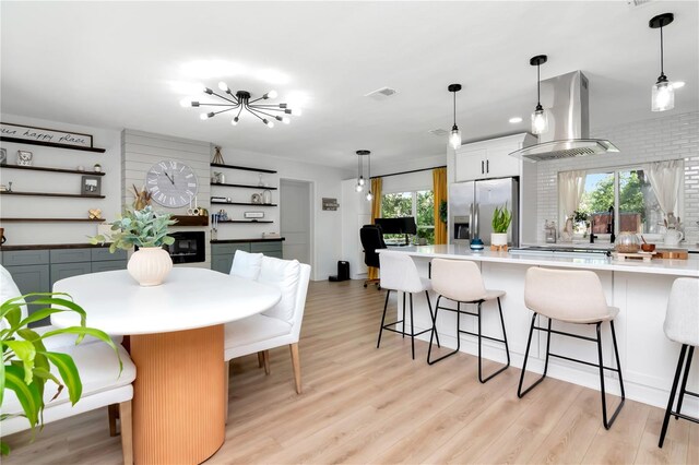 125 Siobhan Ave, Tampa, FL 33613 - kitchen with a kitchen breakfast bar, stainless steel refrigerator with ice dispenser, light wood-style floors, visible vents, and wall chimney exhaust hood