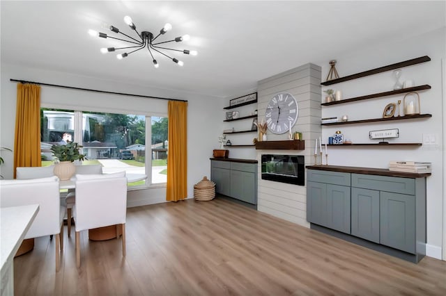 125 Siobhan Ave, Tampa, FL 33613 - kitchen with open shelves, a chandelier, wood counters, light wood finished floors, and a glass covered fireplace