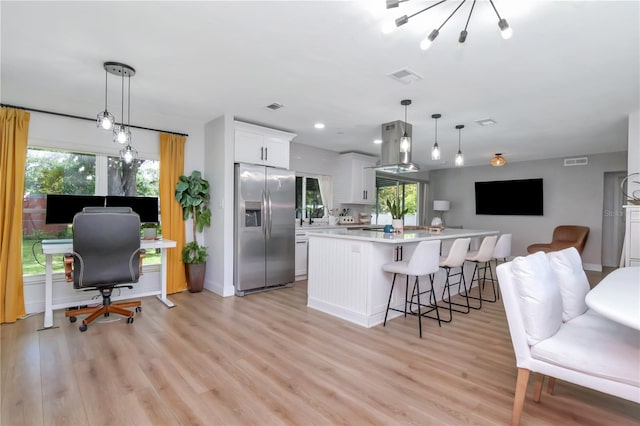 125 Siobhan Ave, Tampa, FL 33613 - kitchen with island range hood, light countertops, stainless steel fridge, and light wood-type flooring