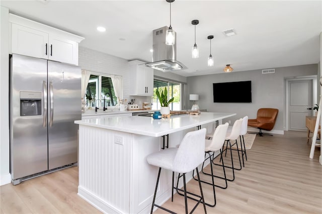 125 Siobhan Ave, Tampa, FL 33613 - kitchen with stainless steel fridge with ice dispenser, a center island, light wood-type flooring, visible vents, and island range hood