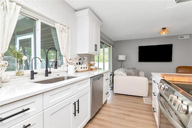 125 Siobhan Ave, Tampa, FL 33613 - kitchen featuring a sink, appliances with stainless steel finishes, open floor plan, light wood-type flooring, and visible vents
