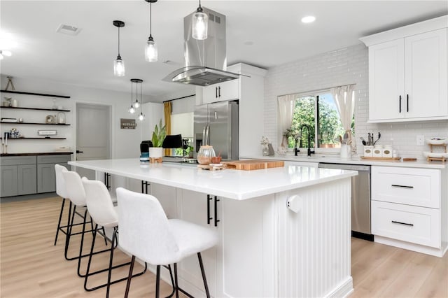125 Siobhan Ave, Tampa, FL 33613 - kitchen with island exhaust hood, a kitchen bar, appliances with stainless steel finishes, light wood-style floors, and a center island
