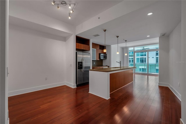 kitchen featuring dark wood-style flooring, stainless steel appliances, baseboards, and dark countertops
