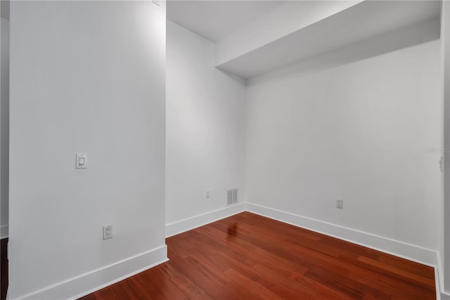 empty room featuring baseboards, visible vents, and dark wood-type flooring