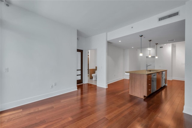 kitchen featuring dark wood-style flooring, stainless steel dishwasher, a sink, visible vents, and a kitchen island with sink