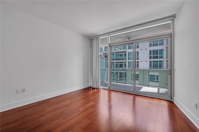 spare room with baseboards, floor to ceiling windows, and wood finished floors