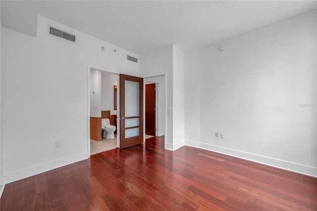empty room featuring baseboards, visible vents, wood finished floors, and french doors