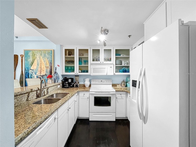 kitchen featuring white appliances, a sink, light stone counters, dark wood-style floors, and glass insert cabinets
