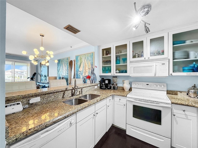kitchen featuring white appliances, a sink, a chandelier, dark wood finished floors, and light stone counters
