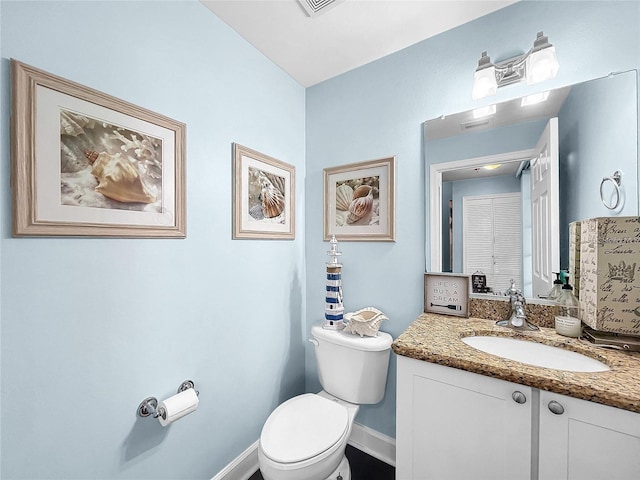half bathroom featuring toilet, baseboards, and vanity