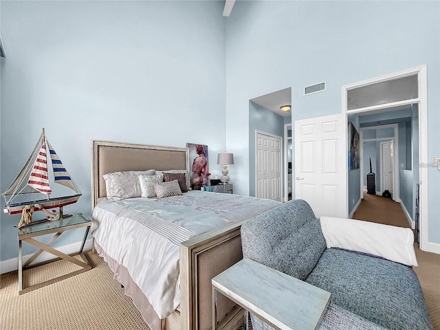 carpeted bedroom with a towering ceiling, baseboards, and a closet