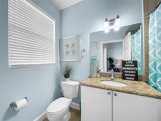 bathroom with toilet, vanity, healthy amount of natural light, and baseboards