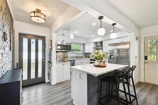 3202 W Coachman Ave, Tampa, FL 33611 - kitchen featuring wall chimney exhaust hood, appliances with stainless steel finishes, wood finished floors, a sink, and light countertops