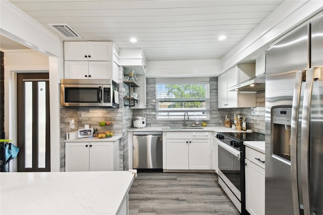 3202 W Coachman Ave, Tampa, FL 33611 - kitchen featuring appliances with stainless steel finishes, wall chimney exhaust hood, light countertops, a sink, and light wood-style floors