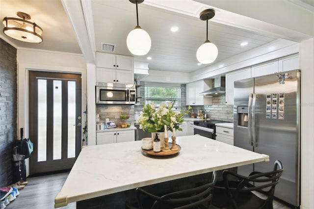3202 W Coachman Ave, Tampa, FL 33611 - kitchen featuring stainless steel appliances, wall chimney exhaust hood, white cabinets, and decorative backsplash