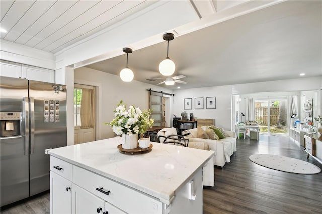 3202 W Coachman Ave, Tampa, FL 33611 - kitchen with stainless steel refrigerator with ice dispenser, a barn door, white cabinets, dark wood-style flooring, and hanging light fixtures
