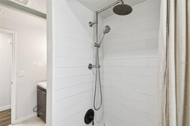 3202 W Coachman Ave, Tampa, FL 33611 - bathroom with a tile shower, vanity, and baseboards