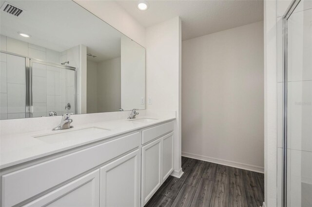 241 Begonia Pl, Poinciana, FL 34759 - bathroom with a stall shower, double vanity, wood finished floors, and a sink