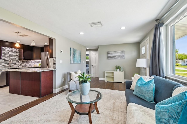 living area with baseboards, visible vents, recessed lighting, and light wood finished floors