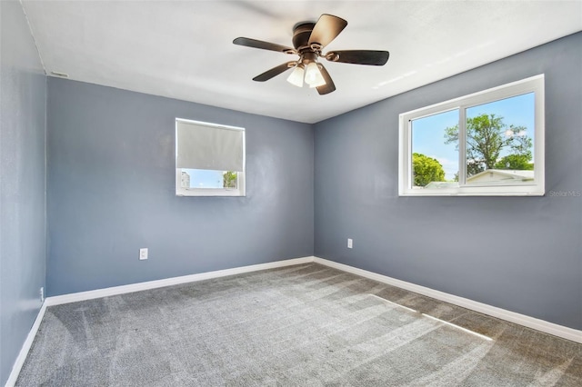 carpeted spare room featuring baseboards, ceiling fan, and a healthy amount of sunlight