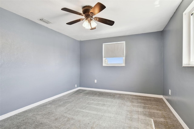 carpeted spare room featuring baseboards, visible vents, and a ceiling fan