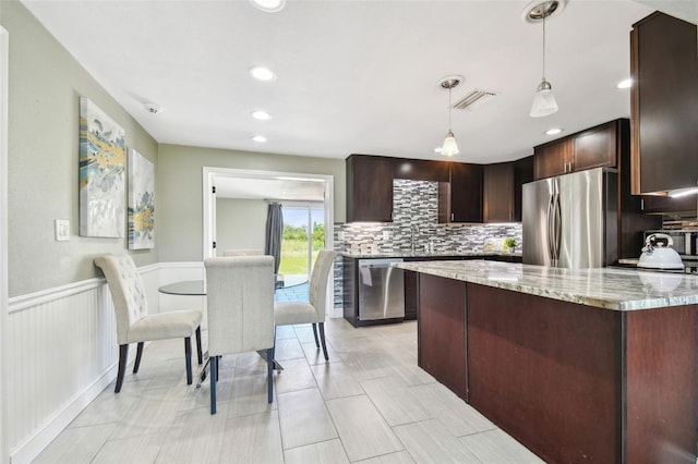 kitchen featuring visible vents, tasteful backsplash, dark brown cabinetry, appliances with stainless steel finishes, and wainscoting