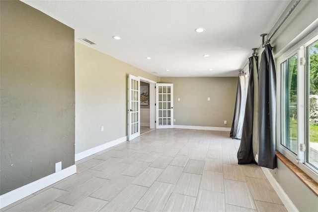 empty room featuring baseboards, visible vents, recessed lighting, and french doors