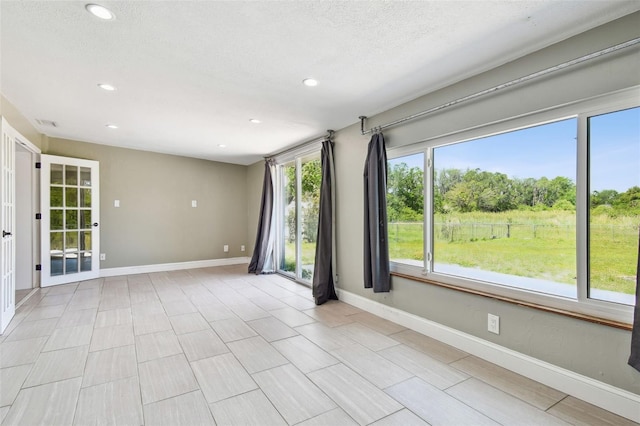 unfurnished room featuring a textured ceiling, baseboards, and recessed lighting