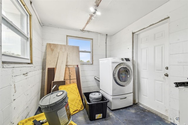 clothes washing area featuring concrete block wall, laundry area, and washer / dryer