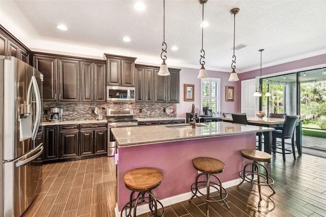 21627 Pearl Crescent Ct, Land O Lakes, FL 34637 - kitchen featuring appliances with stainless steel finishes, visible vents, decorative backsplash, a sink, and wood finished floors