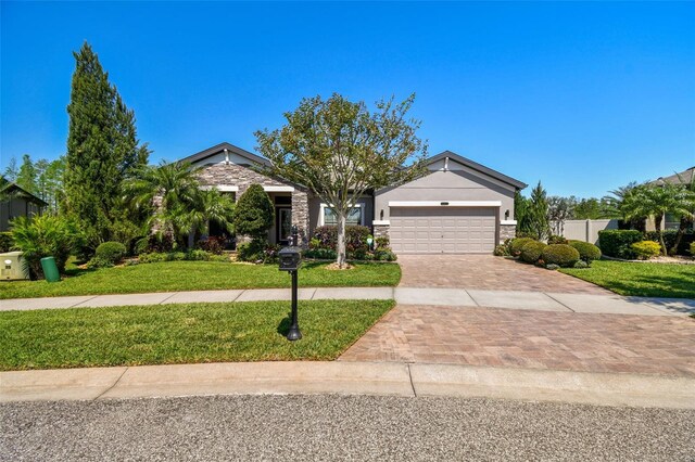 21627 Pearl Crescent Ct, Land O Lakes, FL 34637 - view of front of home with a front lawn, stone siding, a garage, and decorative driveway