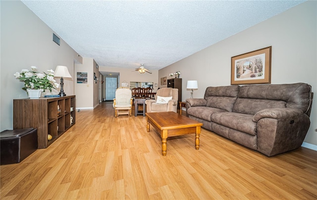 living area with light wood finished floors, a textured ceiling, baseboards, visible vents, and a ceiling fan