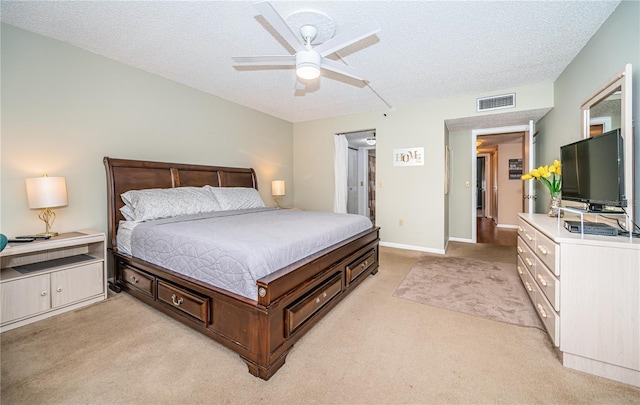 bedroom with light carpet, a ceiling fan, visible vents, and a textured ceiling