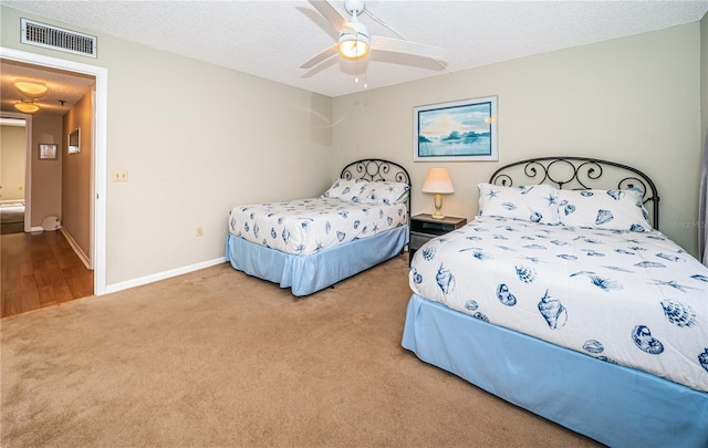 carpeted bedroom featuring a textured ceiling, visible vents, baseboards, and ceiling fan