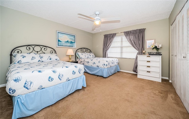 carpeted bedroom featuring baseboards, a textured ceiling, a closet, and ceiling fan