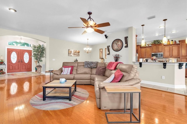 12304 Freesia Ct, Riverview, FL 33569 - living room featuring light wood finished floors, visible vents, and ceiling fan with notable chandelier