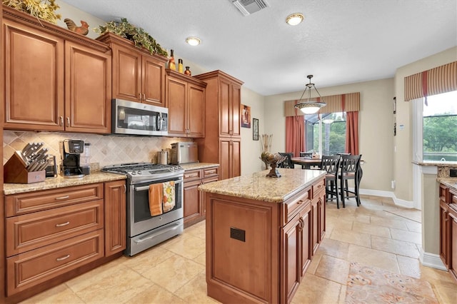 12304 Freesia Ct, Riverview, FL 33569 - kitchen with visible vents, plenty of natural light, appliances with stainless steel finishes, brown cabinetry, and backsplash