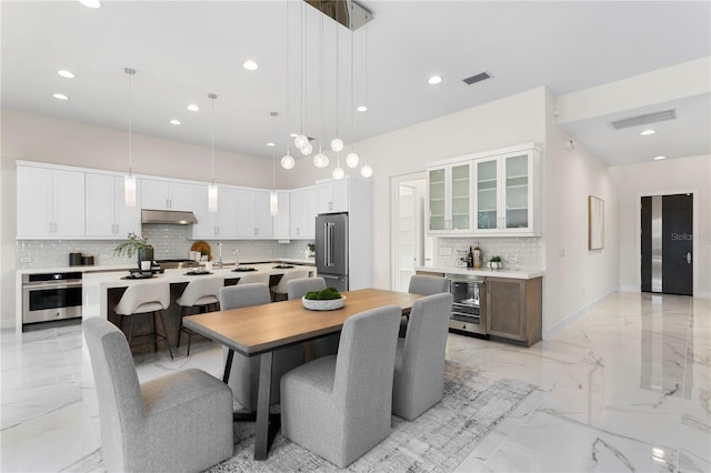 dining space featuring marble finish floor, visible vents, beverage cooler, and bar