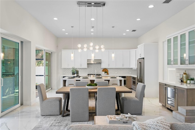 dining space featuring marble finish floor, recessed lighting, and beverage cooler