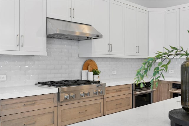 kitchen featuring backsplash, white cabinets, appliances with stainless steel finishes, and under cabinet range hood