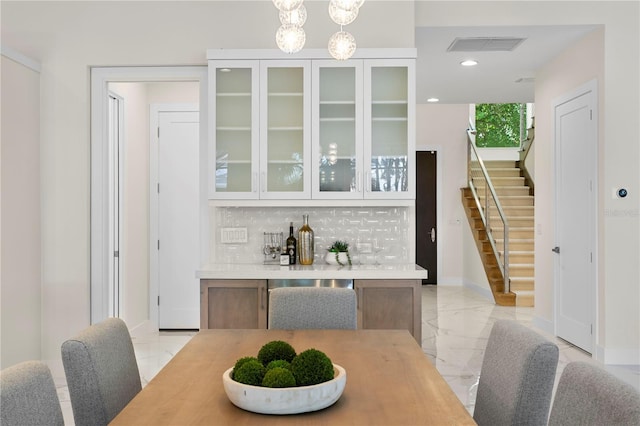 dining room featuring stairs, baseboards, marble finish floor, a dry bar, and visible vents