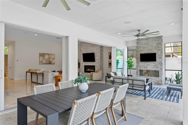 view of patio with an outdoor living space with a fireplace, outdoor dining space, and ceiling fan