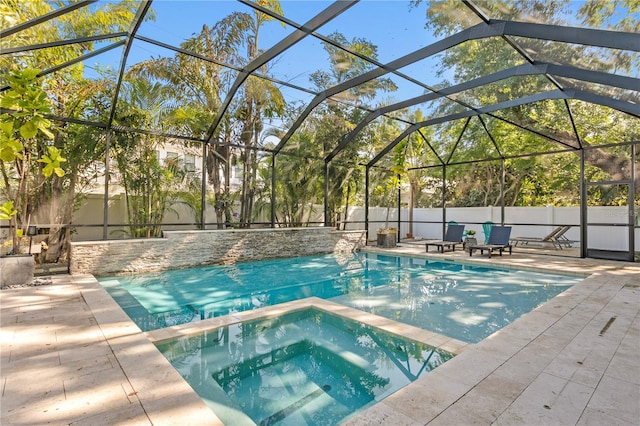 view of pool featuring a pool with connected hot tub, glass enclosure, fence, and a patio area