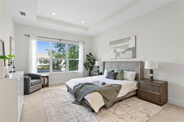 bedroom with a tray ceiling, baseboards, light colored carpet, visible vents, and recessed lighting