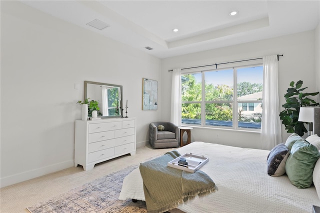 bedroom with a tray ceiling, light colored carpet, recessed lighting, baseboards, and visible vents
