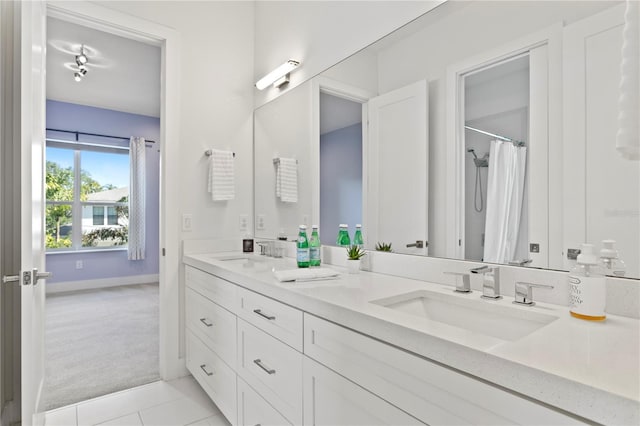 full bathroom featuring a shower with curtain, double vanity, a sink, and baseboards