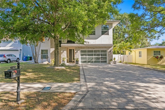 view of front of property featuring fence, a front yard, decorative driveway, and a garage